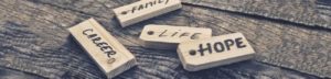 Stock photo of tiles that say from left to right: Career, Family, Life, Hope. They are scattered on wood.