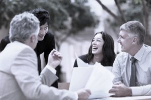 Several business people discuss documents outside.