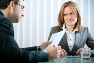 A business woman gives a sideways, disapproving glance to a male colleague who is reviewing a document next to her.
