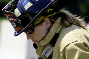 This image shows a close-up of a female firefighter's face. She is dressed for a fire.