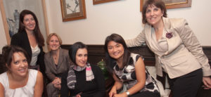 Several women sit on a couch and smile for the camera at the HLAW event.