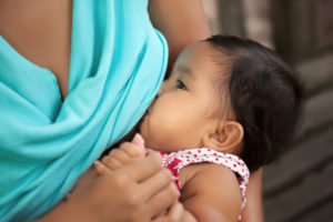 A baby breastfeeds at his mom's chest. Only the baby is visible.
