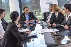 A group of business people sit at a conference table having a discussion.