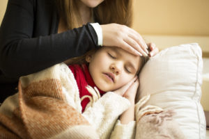 Closeup photo of caring mother holding head on sick daughter forehead
