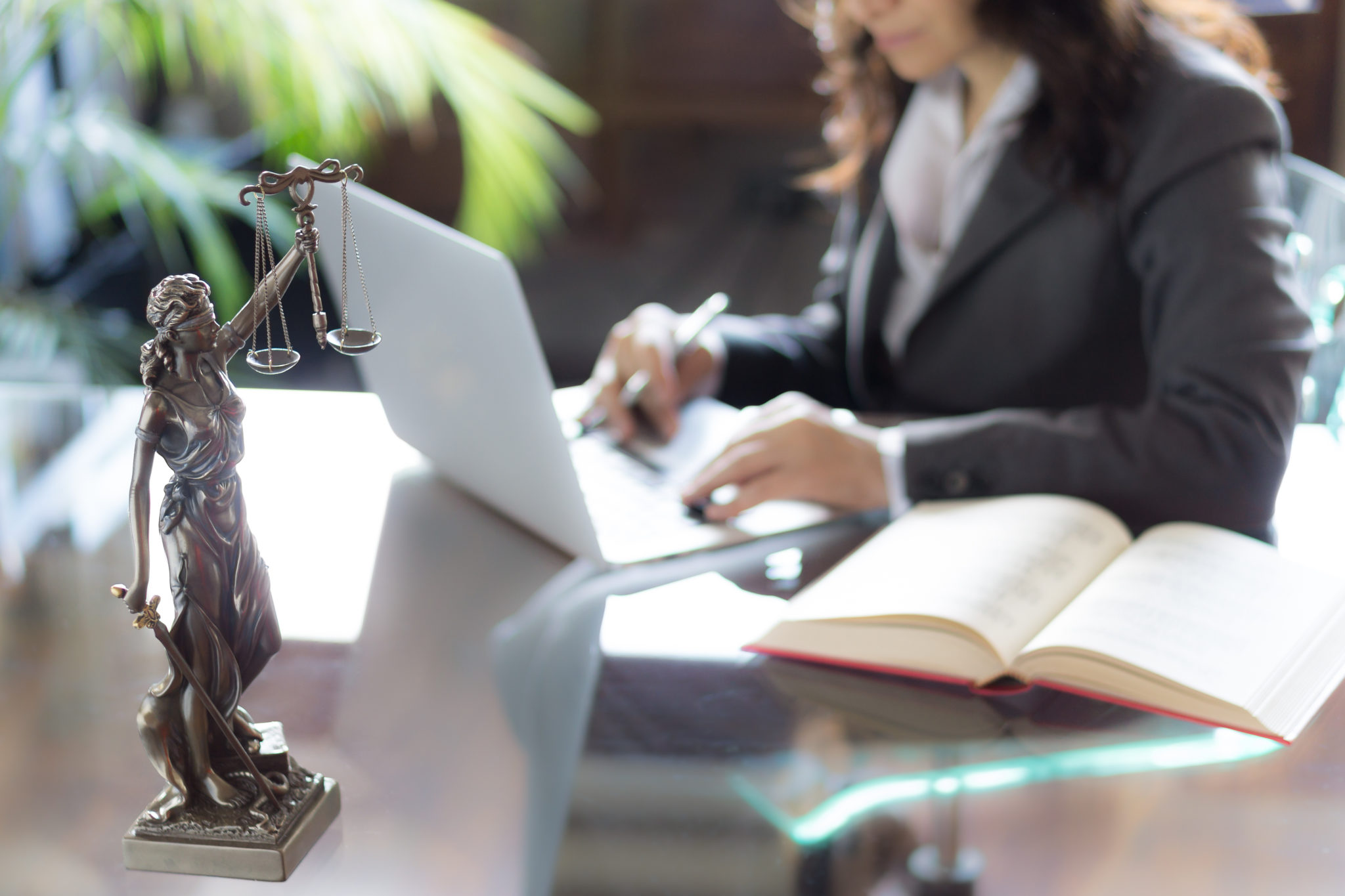 Lawyer office. Statue of Justice with scales and lawyer working on a laptop. Legal law, advice and justice concept